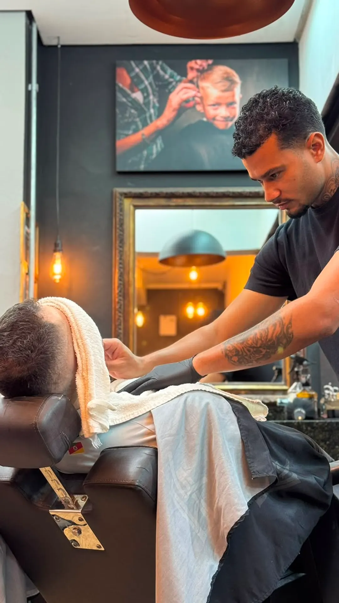 Barbeiro da Queiroz Barber Club em Viamão finalizando o atendimento com toalha quente
